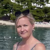 WPF Community - Eine blonde Frau mit Sonnenbrille auf dem Kopf blickt in die Kamera, mit See und Bäumen im Hintergrund.