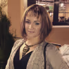 WPF Community - Eine Frau mit kurzen Haaren und Pony, einem schwarzen Top und einer beigen Strickjacke.