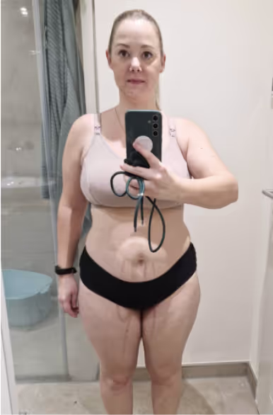 Eine Frau in Sport-BH und Unterwäsche macht ein Selfie im Spiegel.